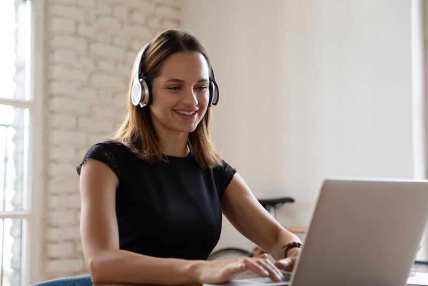 Junge Frau lernt mit Headset am Laptop - FHH Academy