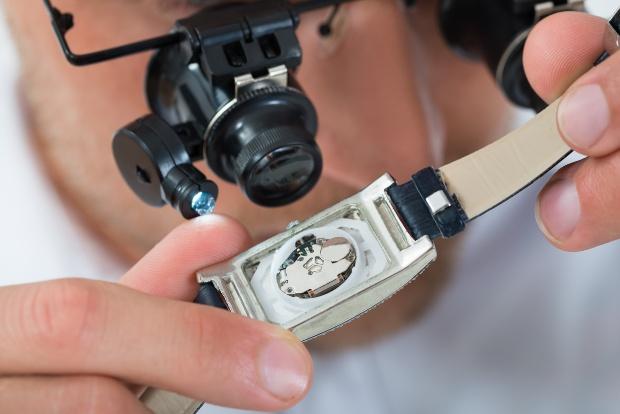 Uhrmacher inspiziert Armbanduhr mit Lupe - Uhr-Revision