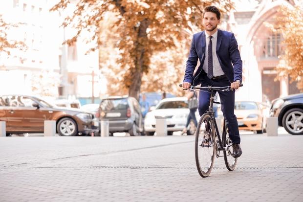 Junger Mann in Anzug auf Fahrrad mit Armbanduhr - H82335131