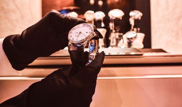 Someone holds luxury watch in hands with gloves