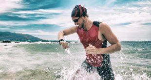 Schwimmer-am-Strand-schaut-auf-Uhr - 5 Sportuhren zum Schwimmen gehen