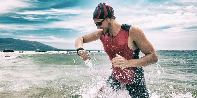 Schwimmer-am-Strand-schaut-auf-Uhr - 5 Sportuhren zum Schwimmen gehen